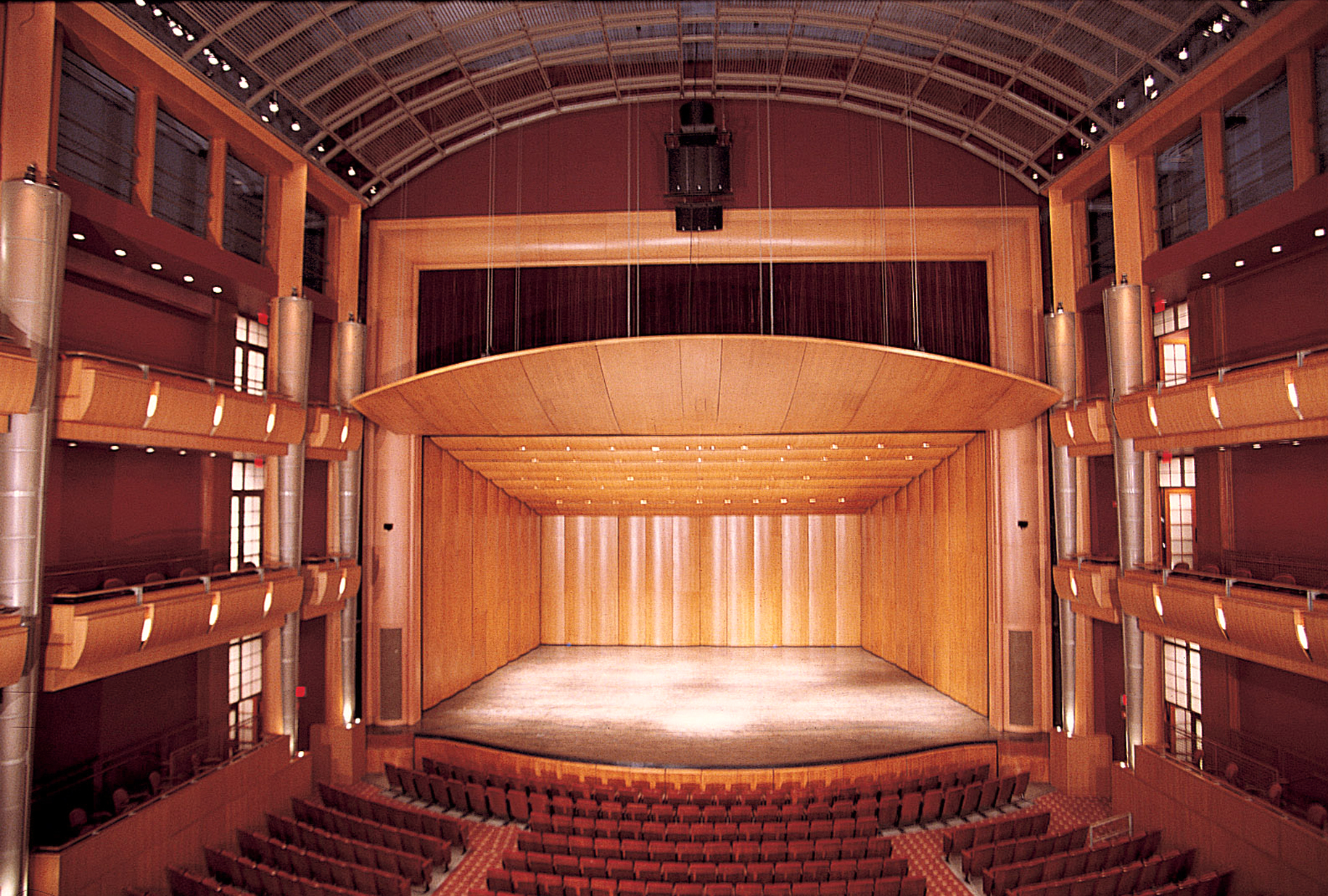 Interior view of our modern concert hall featuring a wooden orchestra shell and seating arrangements. The architectural design highlights the spacious, elegant atmosphere intended for performances.